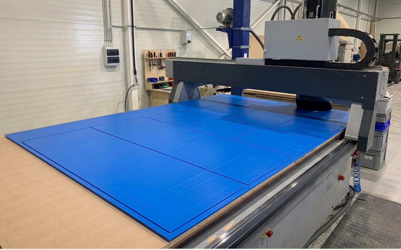 Saját nagy formátumú CNC marógépünk kék HDPE műanyag táblával, tiszta üzemi környezetben